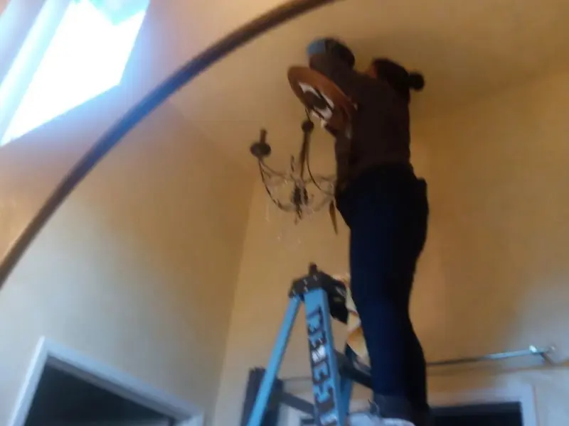 Electrician installing a chandelier in a Piney Green residence
